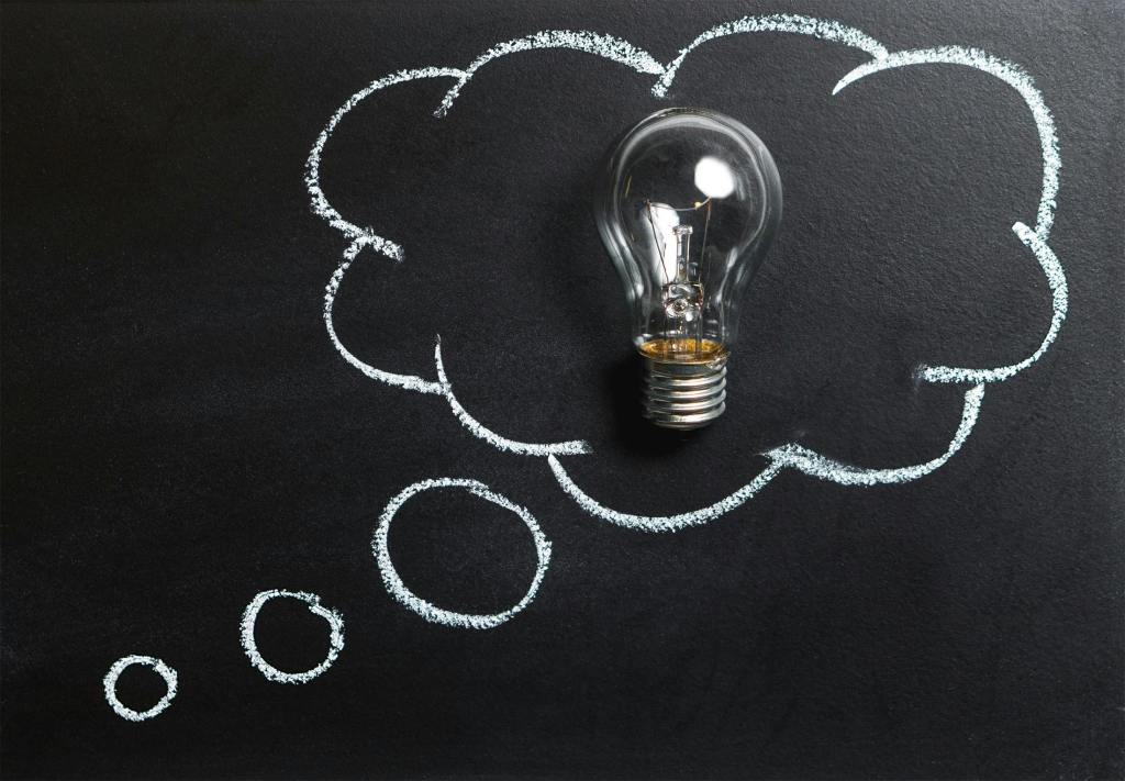 A light bulb placed over a chalkboard, surrounded by chalk-drawn thought bubbles.